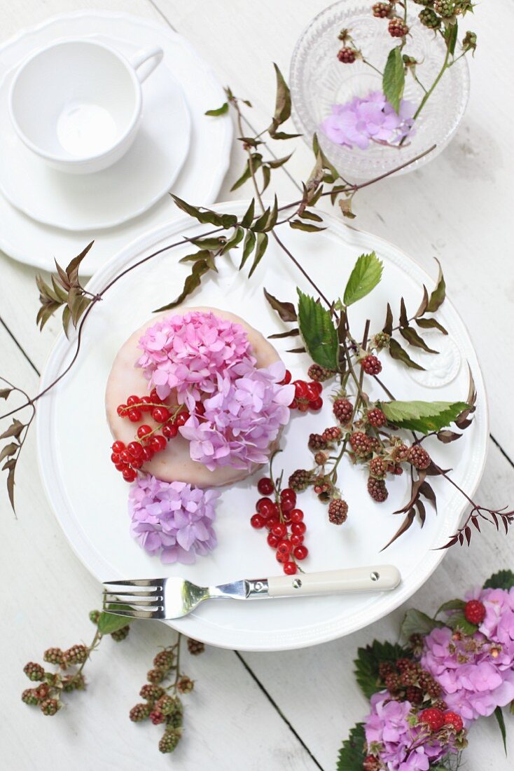 Kleiner Kuchen mit Blumen und Beeren auf der Kaffeetafel