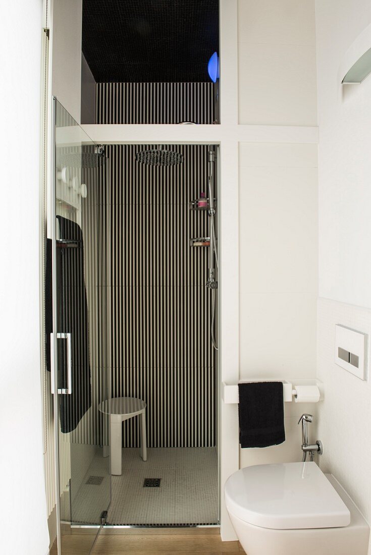 Floor-level shower and striped wall in small bathroom
