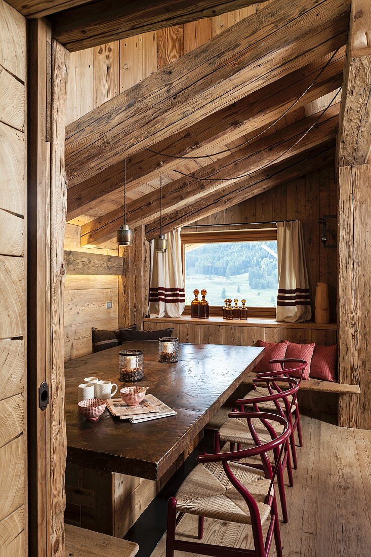 Classic chairs in rustic dining area below chunky wooden roof beams
