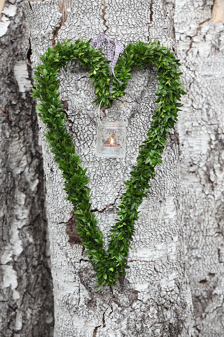 Candle lantern in heart-shaped box wreath hung on tree
