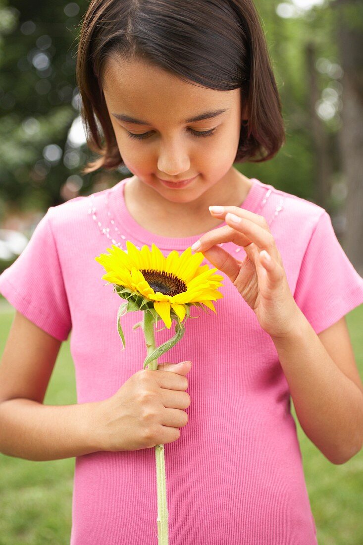 Girl wearing pink T-shirt holding a sunflower