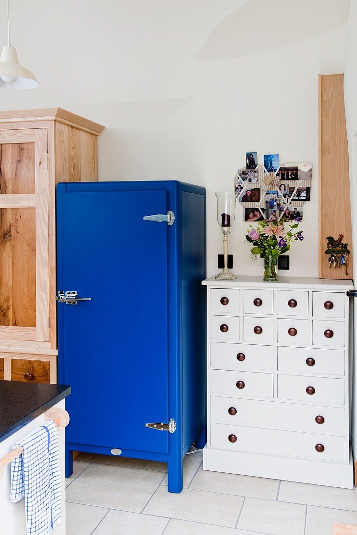 Blauer Kühlschrank neben weißem Schubladenschrank in Landhausküche