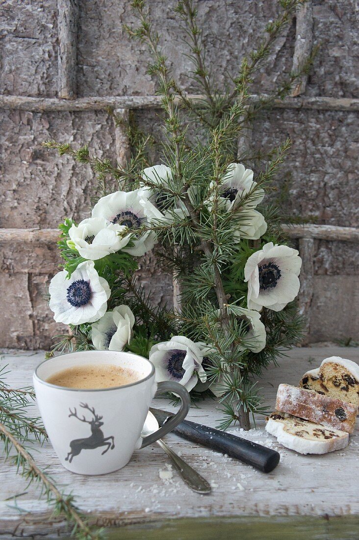 Cup with stag motif and sliced stollen in front of wreath of anemones