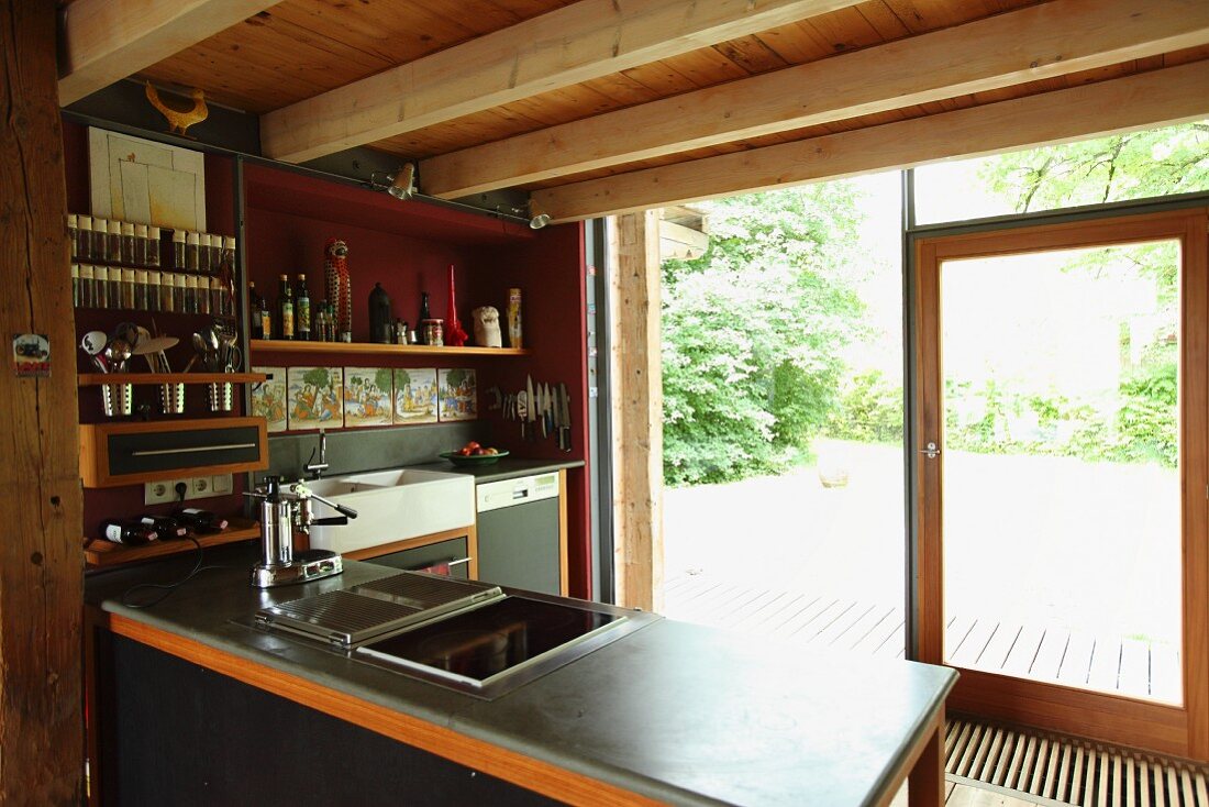 Wood-beamed ceiling in open-plan kitchen with view of garden