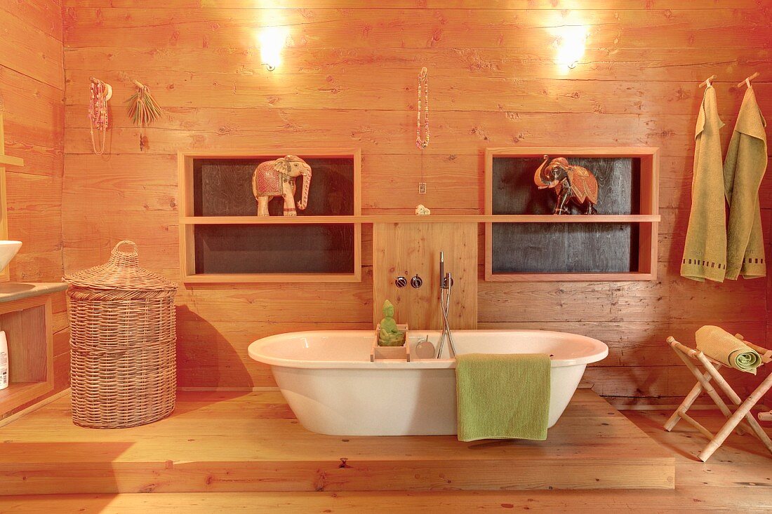 weiße freistehende Badewanne in modernem, holzverkleidetem Bad mit Elefantenfiguren