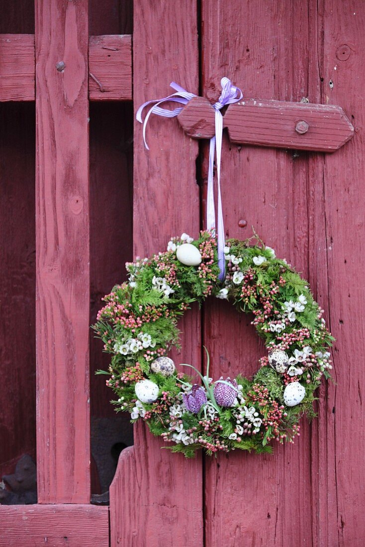 Romantic Easter wreath hung on claret-red garden gate