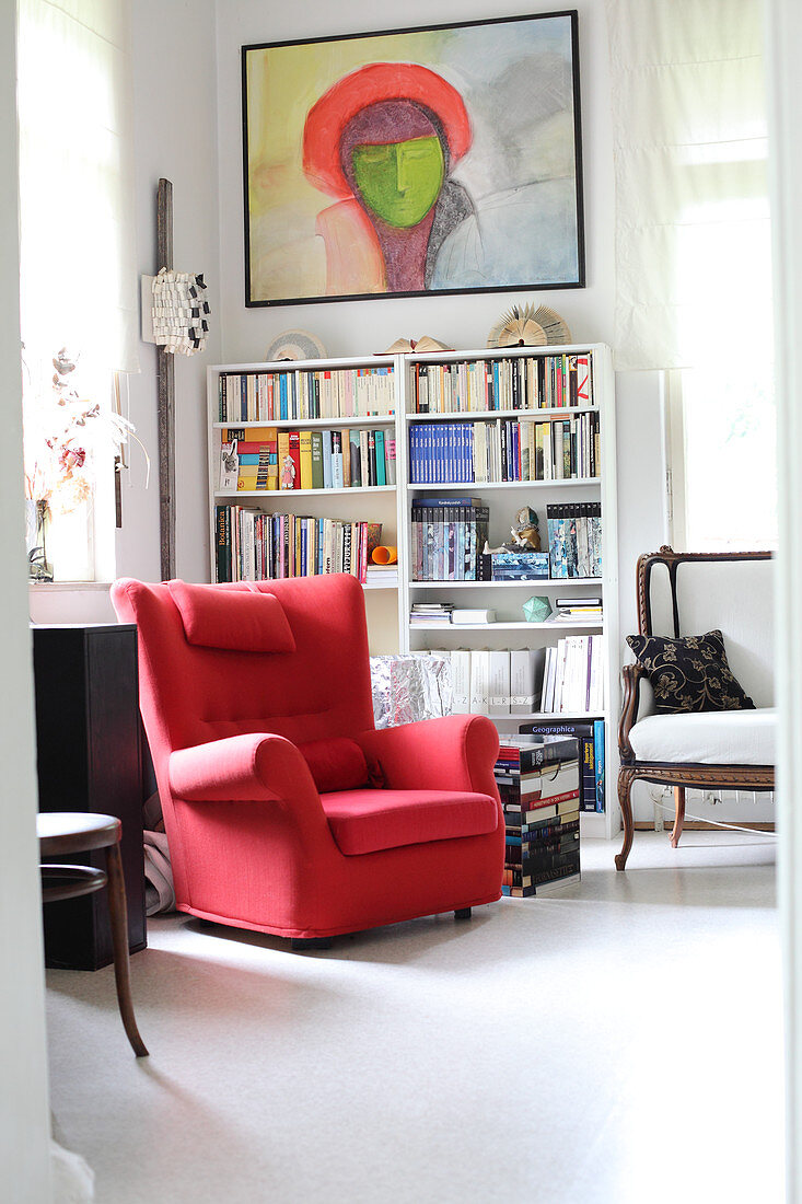 Red armchair and bookcase in study