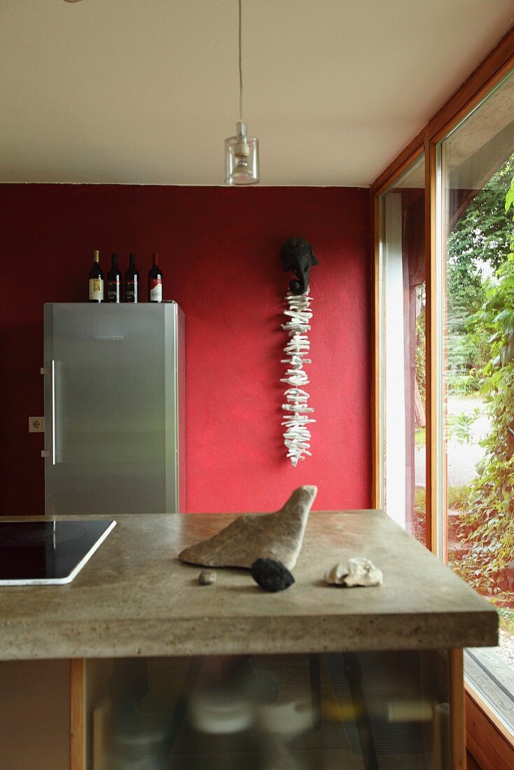 Kücheninsel mit Betonarbeitsplatte vor roter Wand