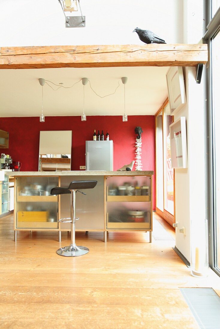 Offene Küche mit Kücheninsel, Barhocker und roter Wand