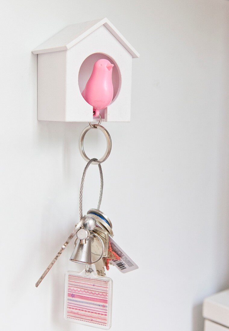 Schlüsselaufbewahrung an weißem Häuschen mit rosafarbener Vogelfigur