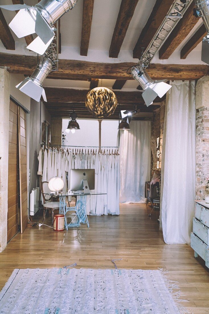 Studio lamps and wooden beams in industrial-style clothes shop