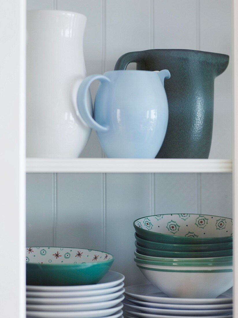 Various jugs, plates and bowls on a white wall shelf