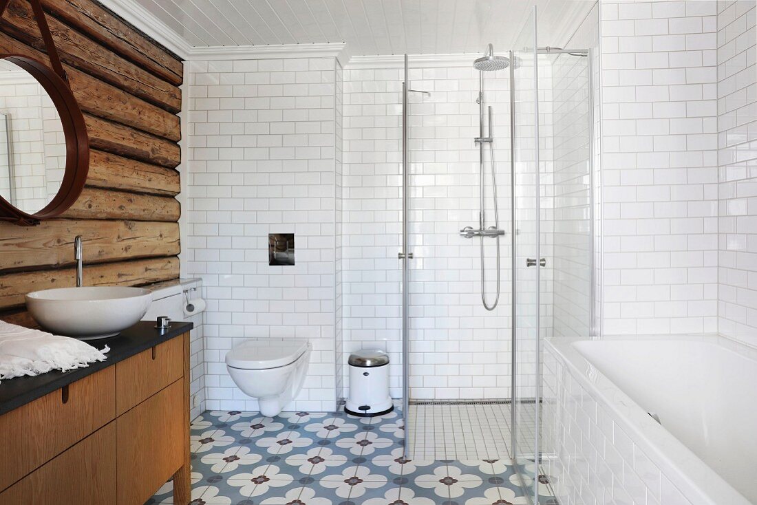 Badezimmer mit rustikaler Holzbohlenwand, Badewanne und verglastem Duschbereich