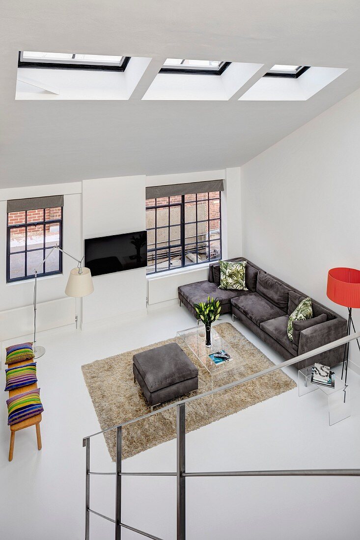 Blick von Treppe auf offenen Wohnbereich mit Industriefenstern, Designermöbeln und Dachfenstern