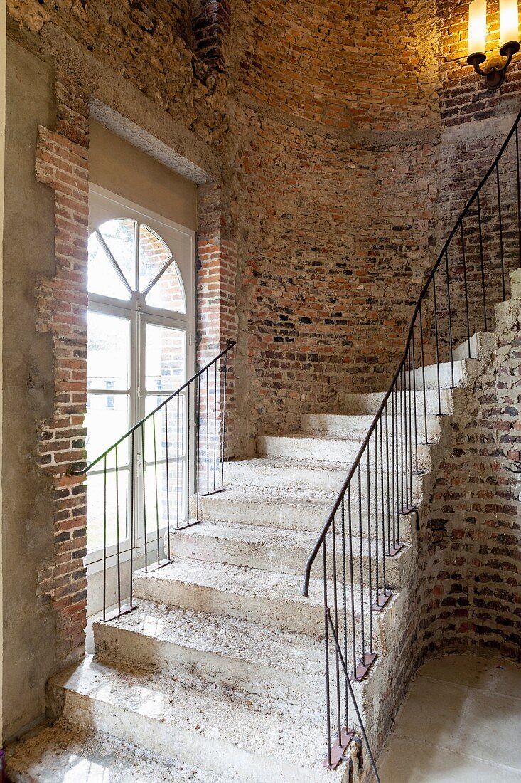 Curved stone staircase against rustic brick wall