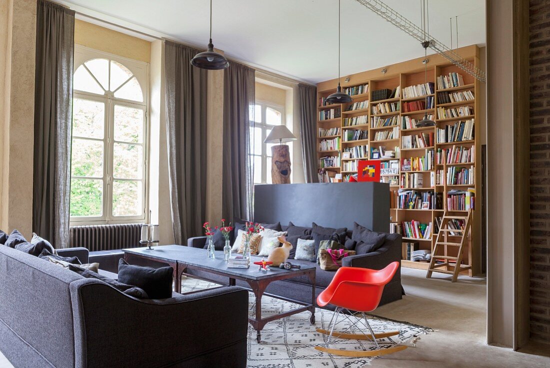 Wohnzimmer mit Raumteilerwand und deckenhohem Bücherregal