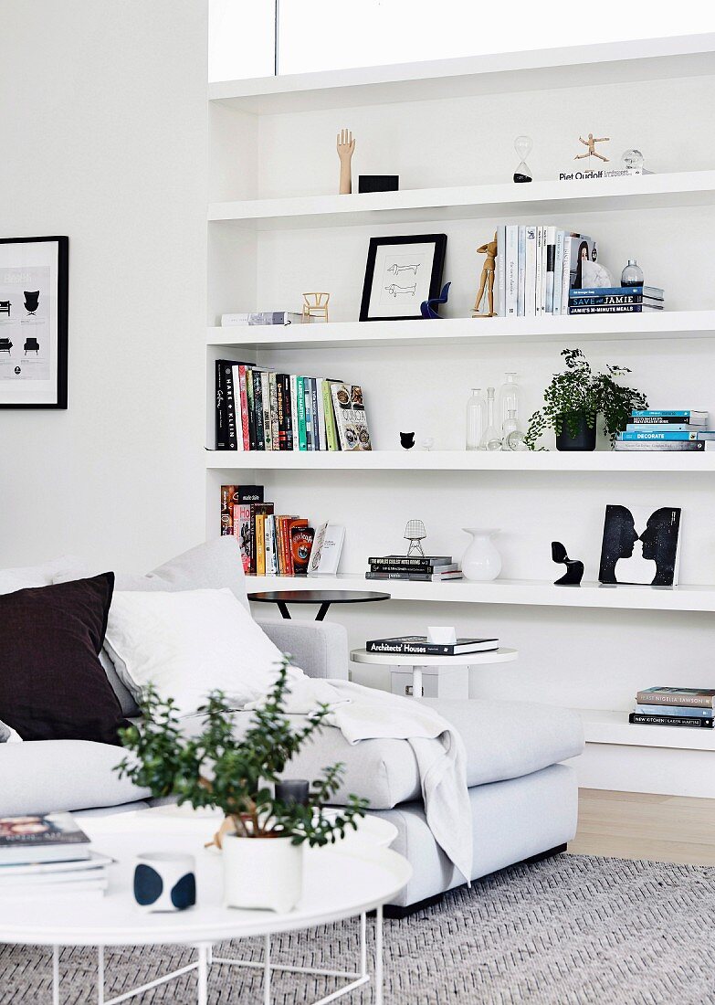 White coffee table and sofa in front of an open shelf