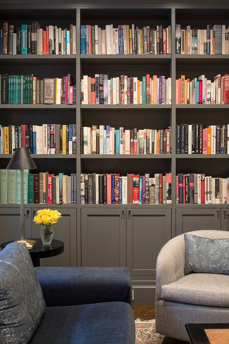 Sofa und Sessel vor grauer Bücherwand