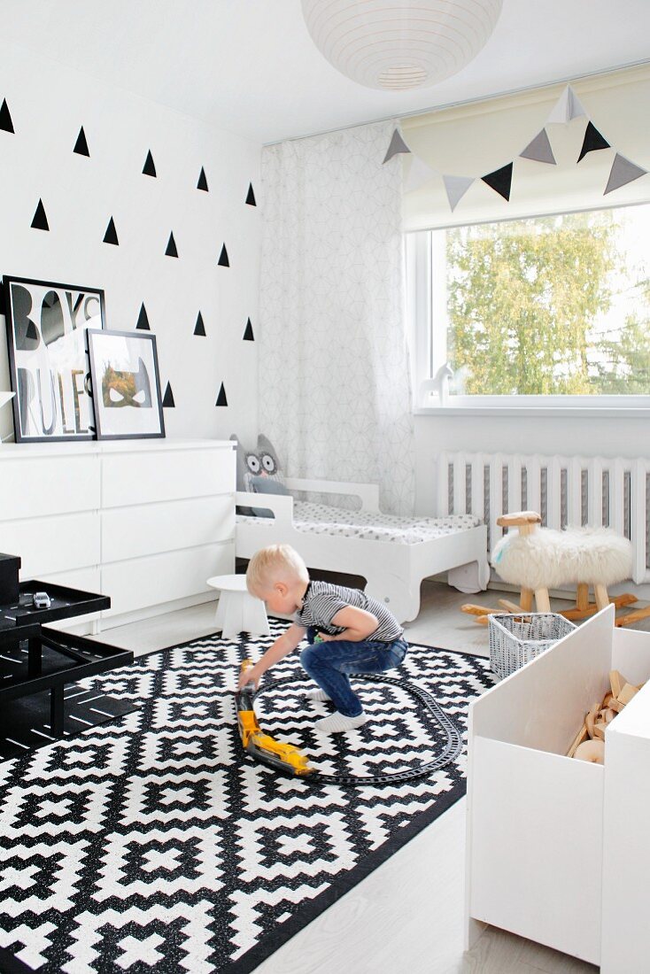 Schwarz-weiss gestaltetes Kinderzimmer mit spielendem Jungen auf Teppich