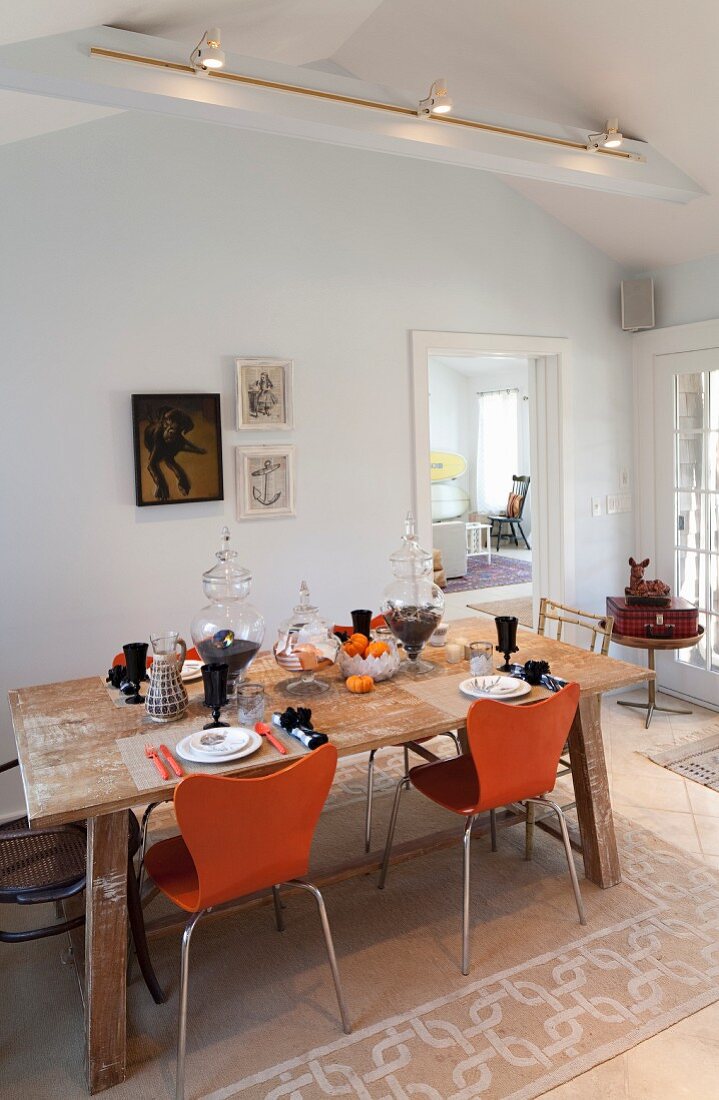Herbstlich gedeckter Esstisch mit orangefarbenen Stühlen
