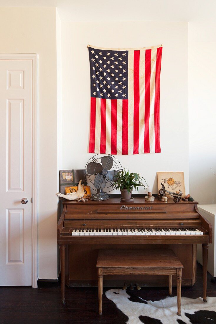 Klavier und Klavierbank vor Wand mit aufgehängter amerikanischer Flagge