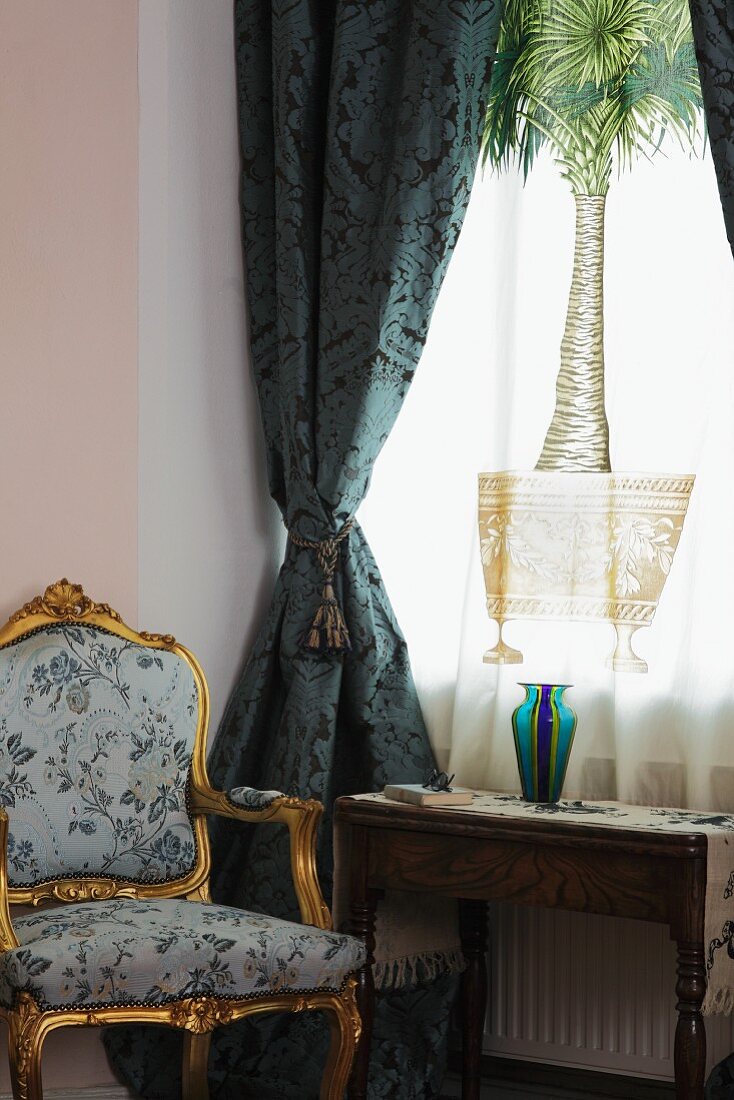 Barocker Sessel vor blauem Vorhang und bedruckter Gardine