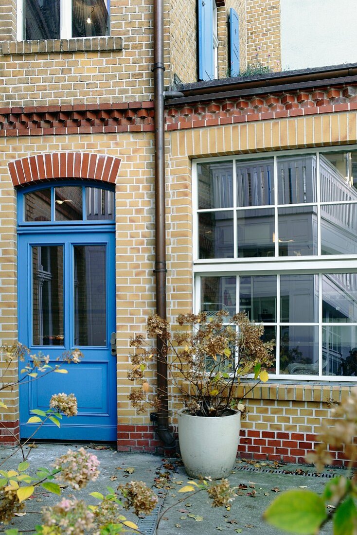 Backsteinfassade mit blauer Tür und Fabrikfenstern