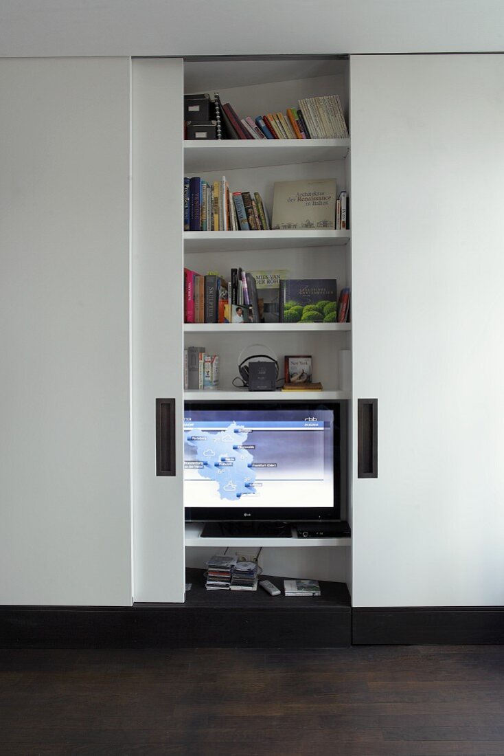 TV and bookcase behind simple, white, sliding doors
