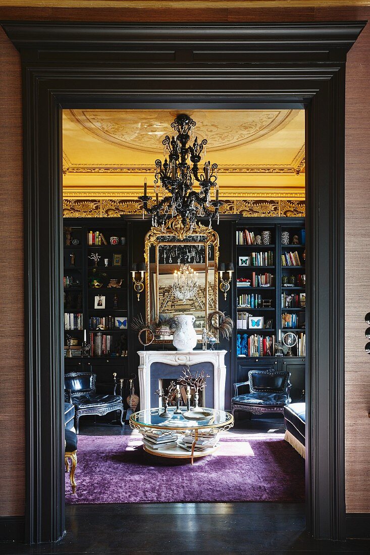 Library with open fire and gilt-framed mirror in historical interior