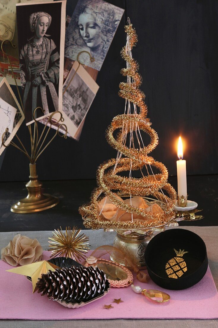 Origineller Weihnachtsbaum aus goldener Girlande auf Etagere mit Kerzenhalter