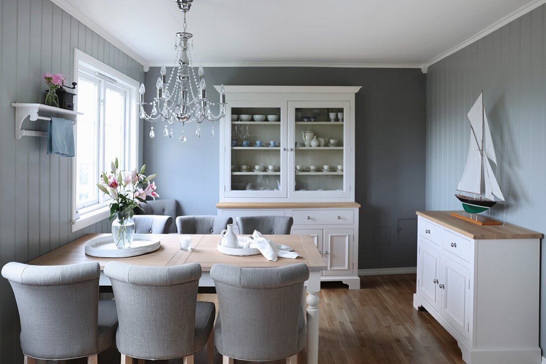 Pale grey upholstered chairs around wooden table in traditional, Scandinavian-style dining room