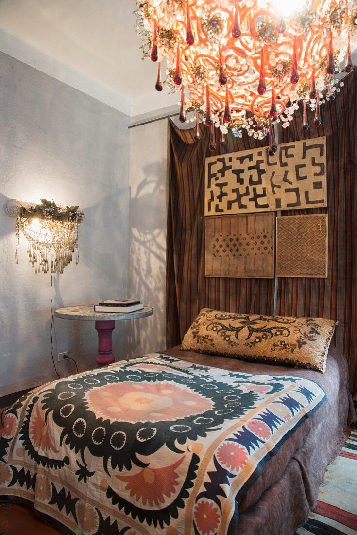 Lamps with glass pendants, ethnic bedspread and ornate pillow in bedroom