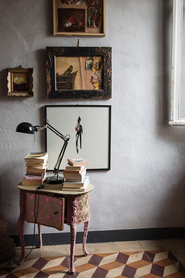 Antiker, stoffbezogener Nachttisch vor Wand mit Bildern
