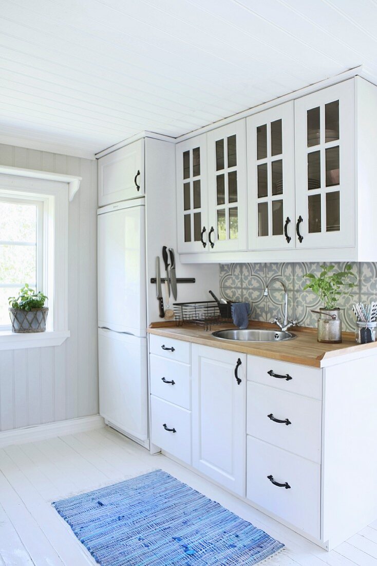 Fitted kitchen with white cupboards and black handles in country-house style