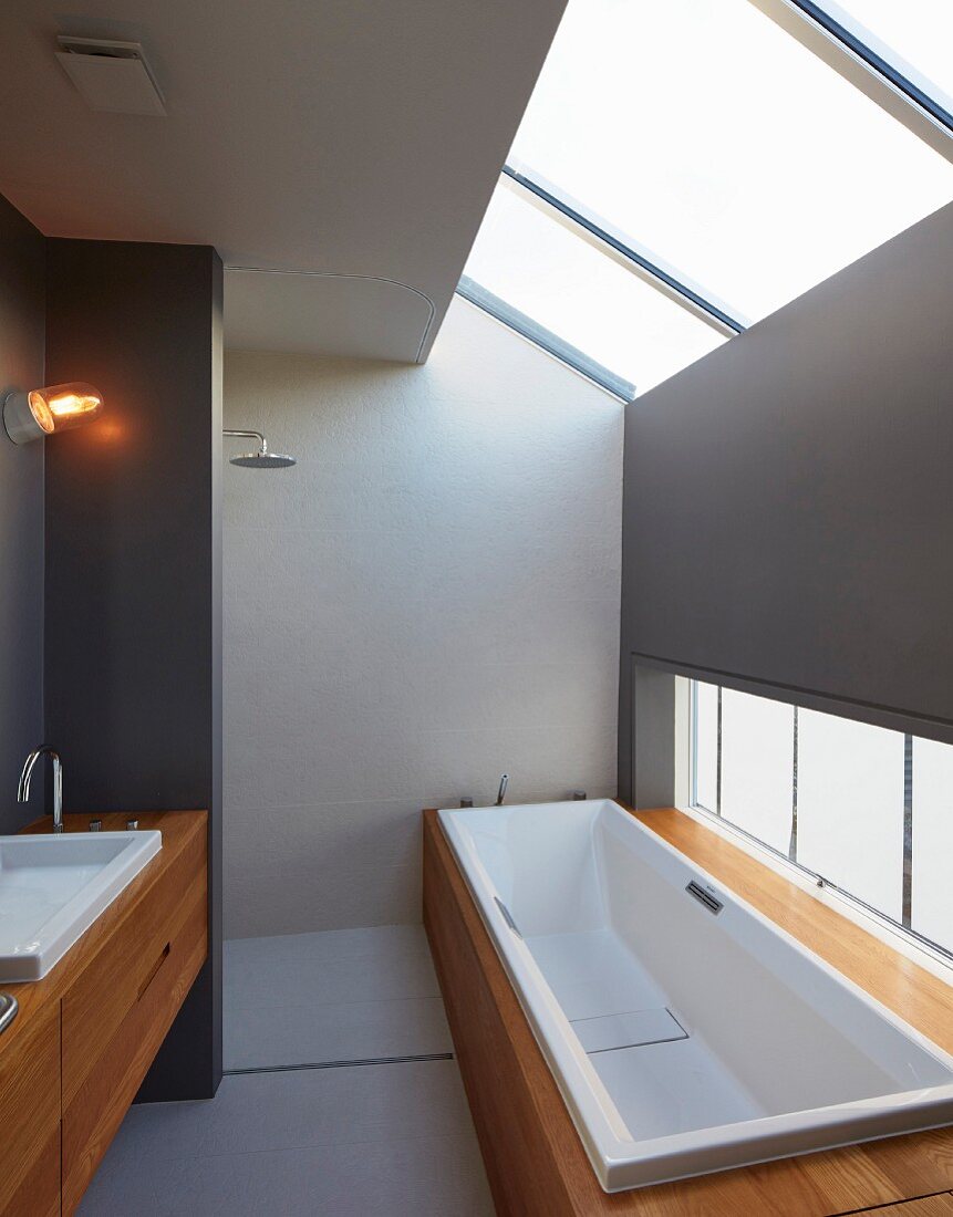 Elegant, minimalist, attic bathroom with shower area, bathtub and exotic-wood installations