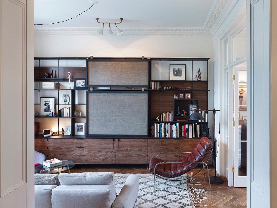 Schrankwand mit Regalsystem und Schiebeelement in elegantem Wohnzimmer mit Retro Ledersessel