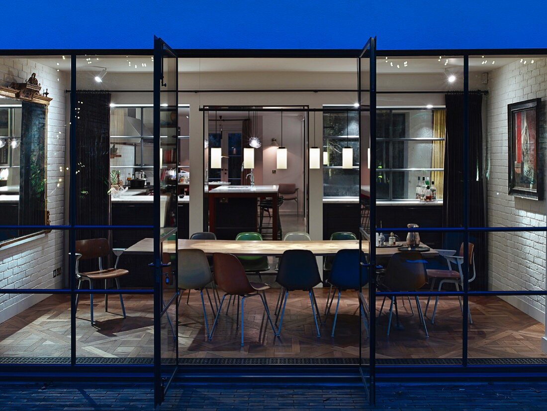 Blick von der Terrasse in Wohnraum mit langem Tisch, Schalenstühlen und eklektischem Ambiente