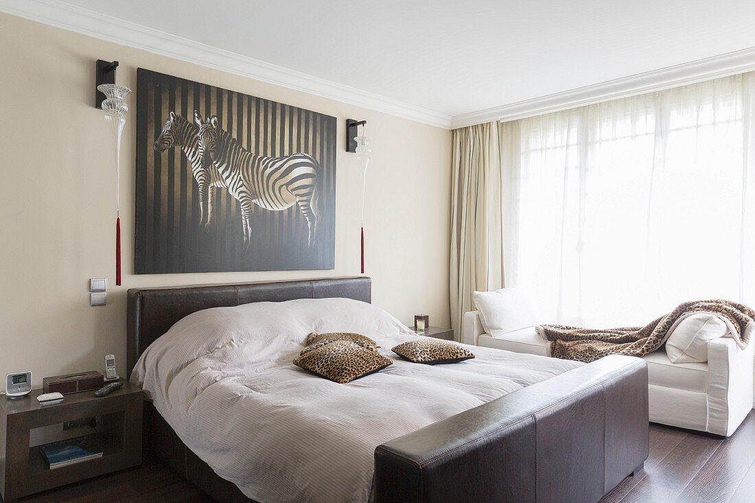 Double bed with leather-covered headboard and foot below picture of zebra in elegant bedroom