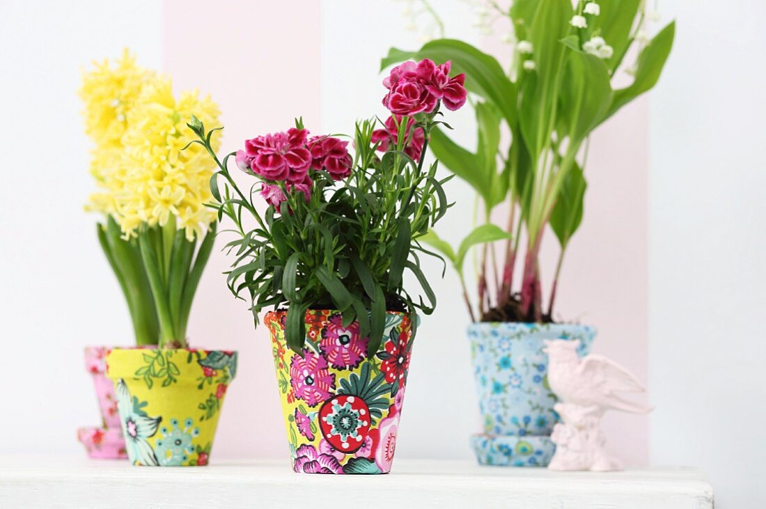 Spring flowers in terracotta pots covered in colourful fabrics