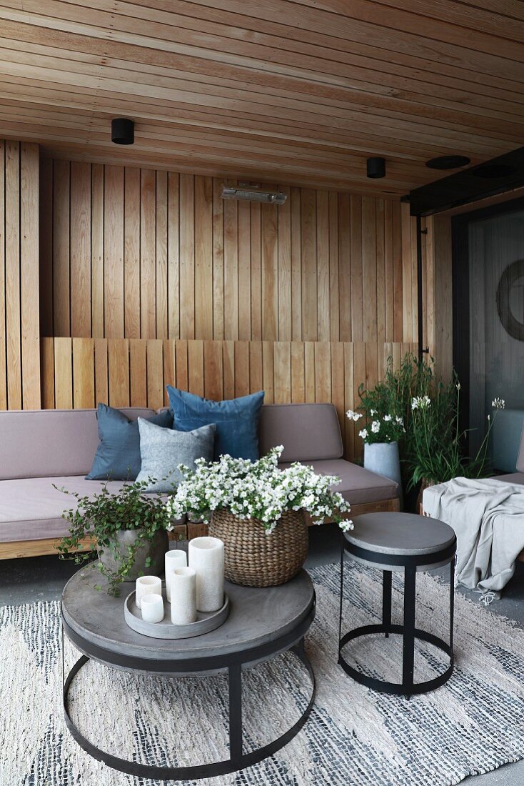 Holzverkleidete moderne Terrasse mit Polstermöbel und runden Tischen