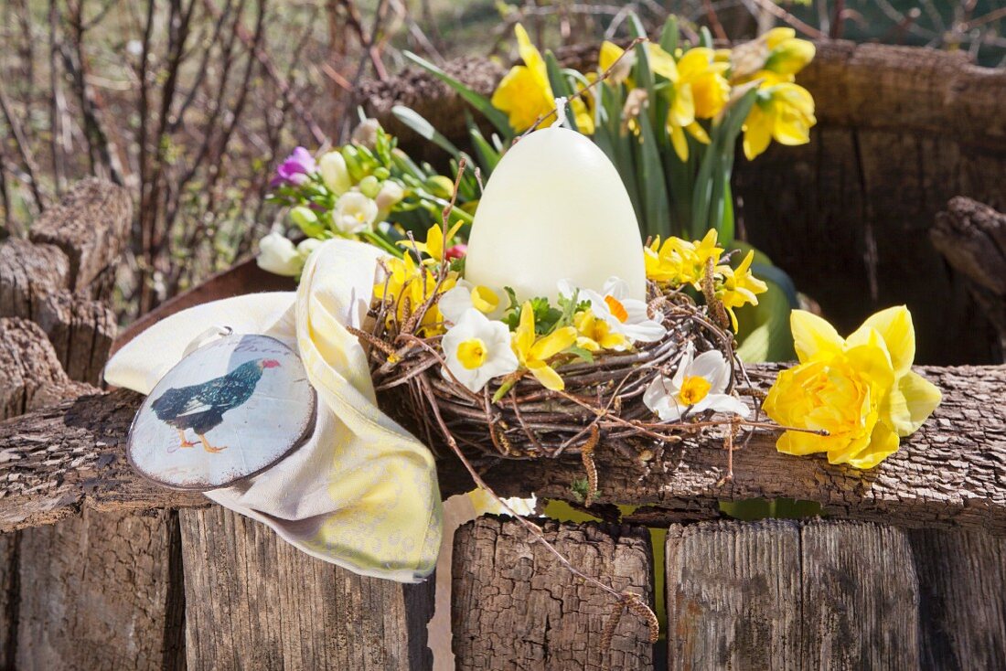 Egg-shaped candles and flowers in Easter nest made from twigs