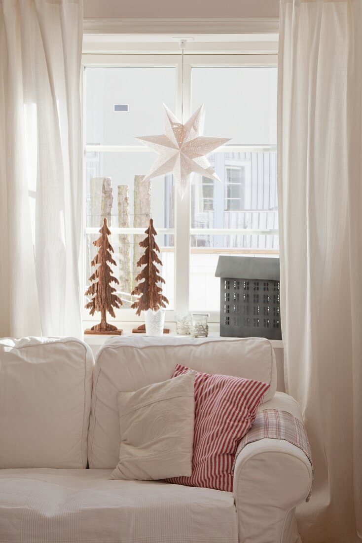 Comfortable loose-covered sofa in front of festively decorated lattice window
