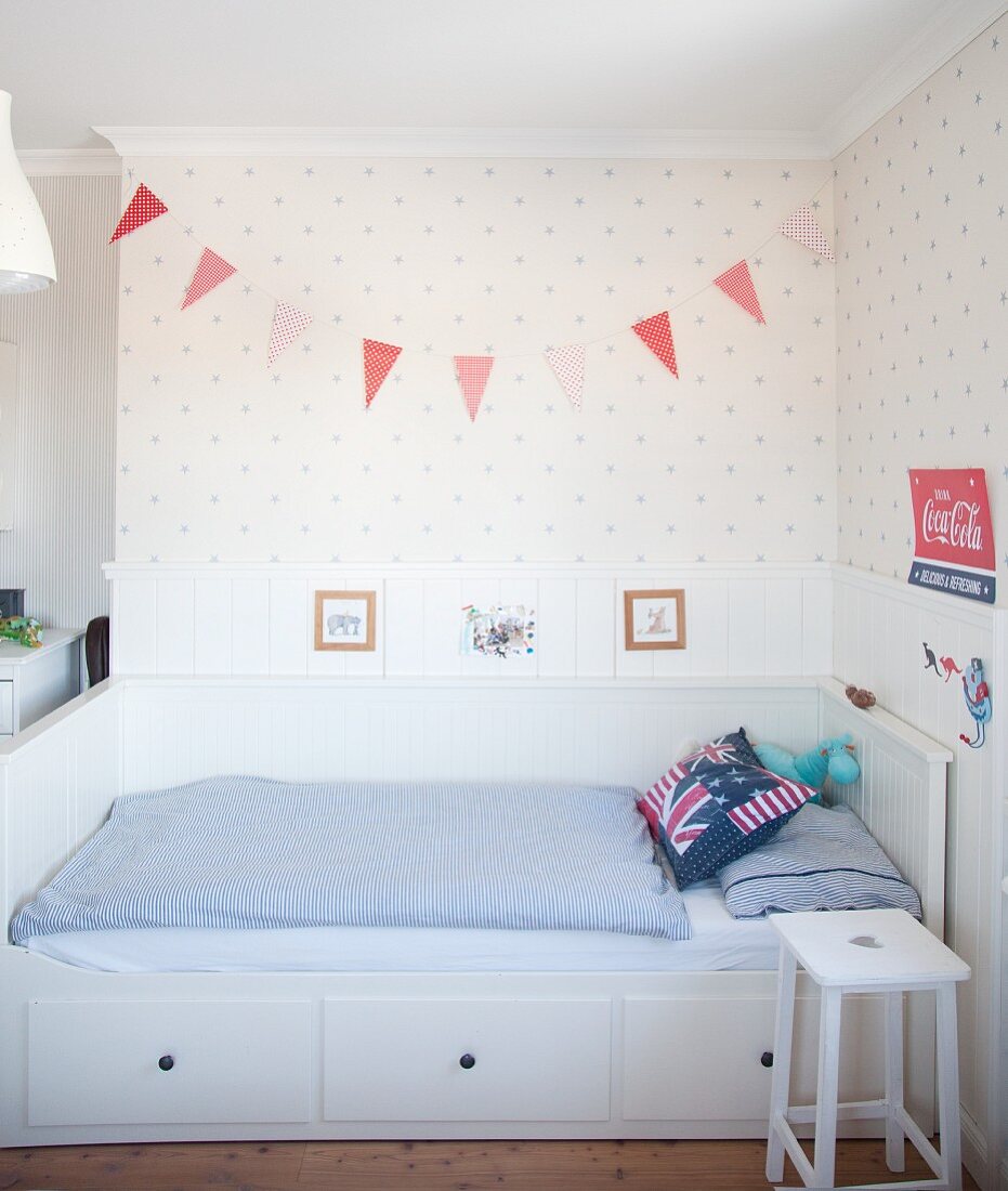 White bed with storage drawers and blue and white bed linen in Scandinavian-style boy's bedroom