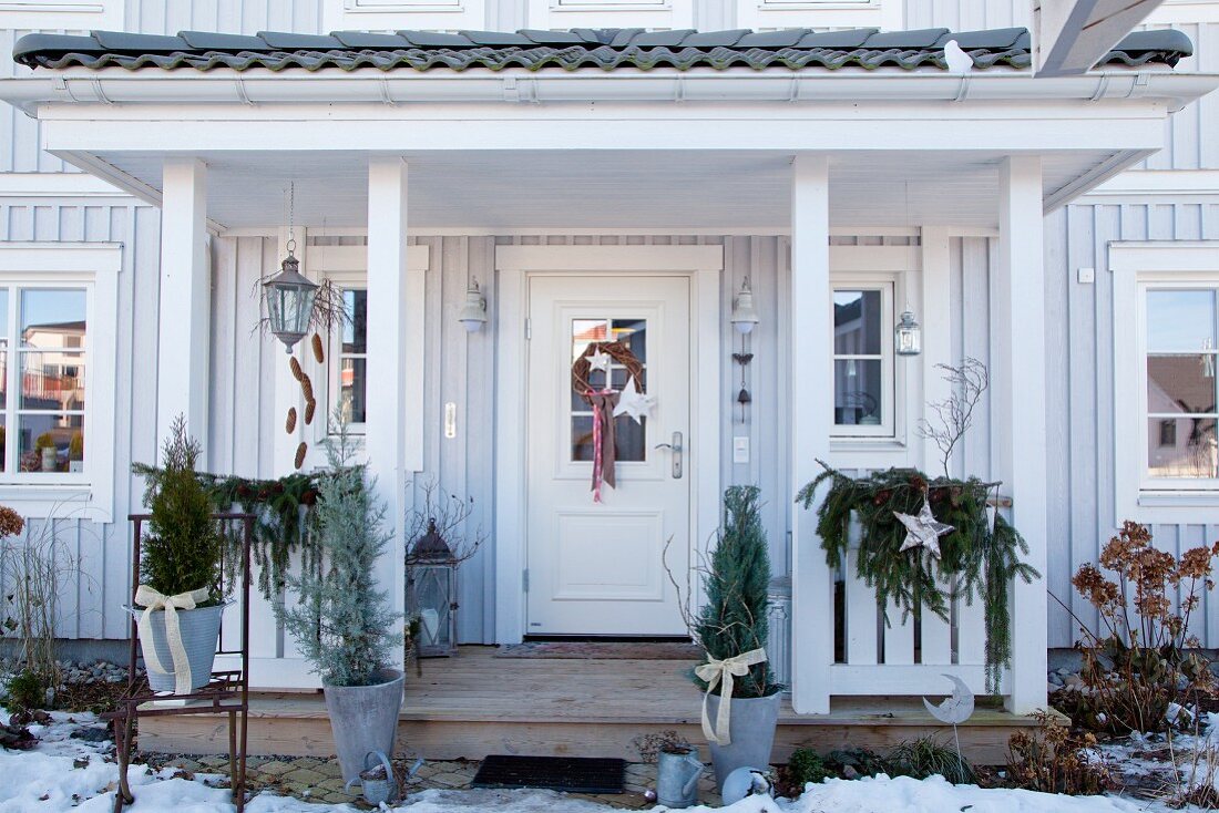 Weihnachtlich geschmückter Eingangsbereich mit Holzpodest und Vordach im skandinavischen Stil