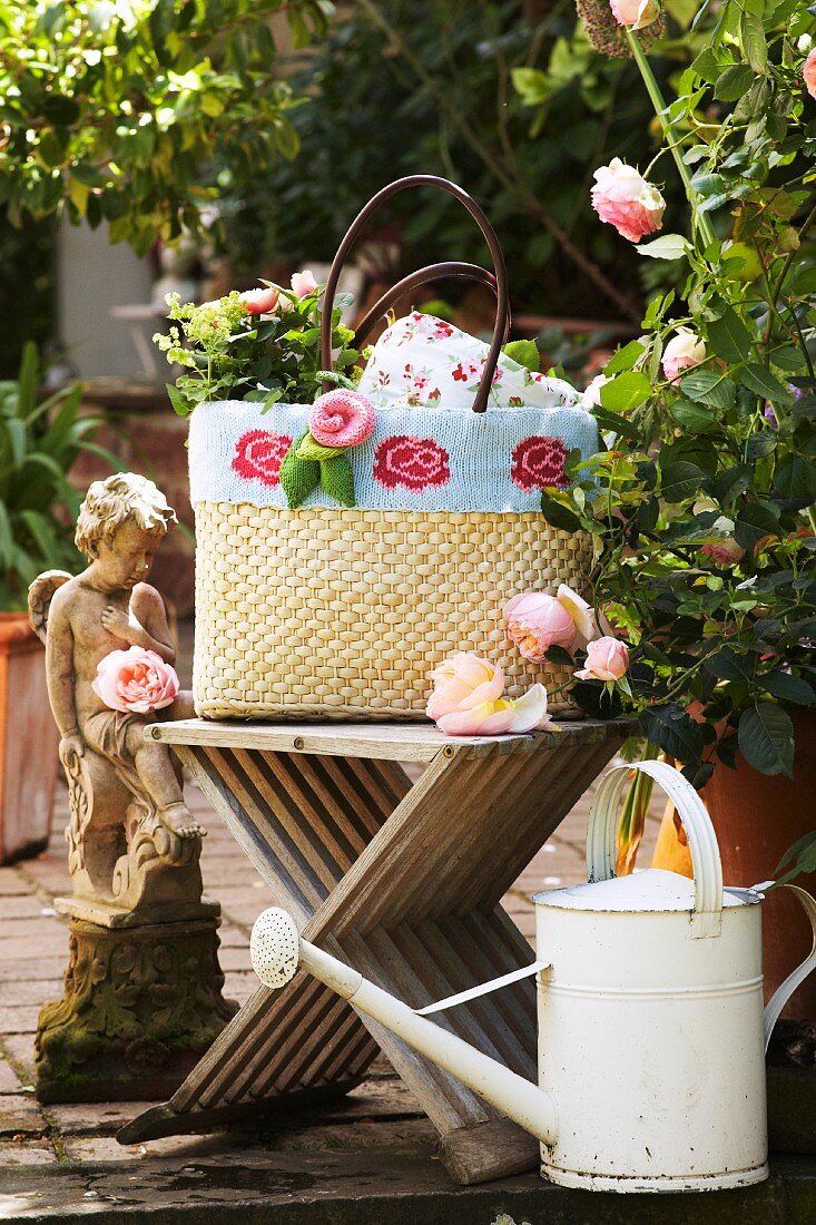 Mit Strickborte und Strickrose verzierte Korbtasche an romantischem Gartenplatz mit Vintage Flair