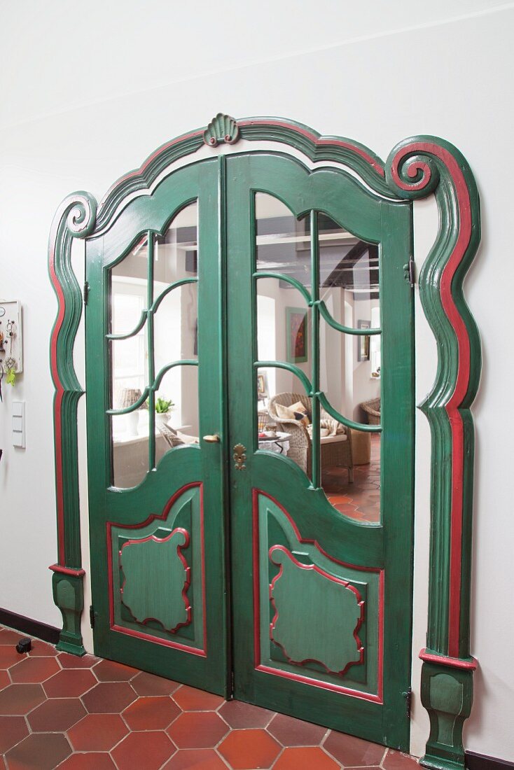 Kunstvoll verzierte Flügeltür mit grüner und roter Lackierung in renoviertem Bauenhaus