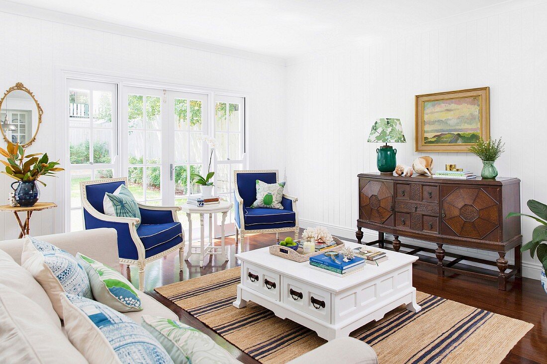 Elegant living room with blue upholstered armchairs, antique furniture and country house flair