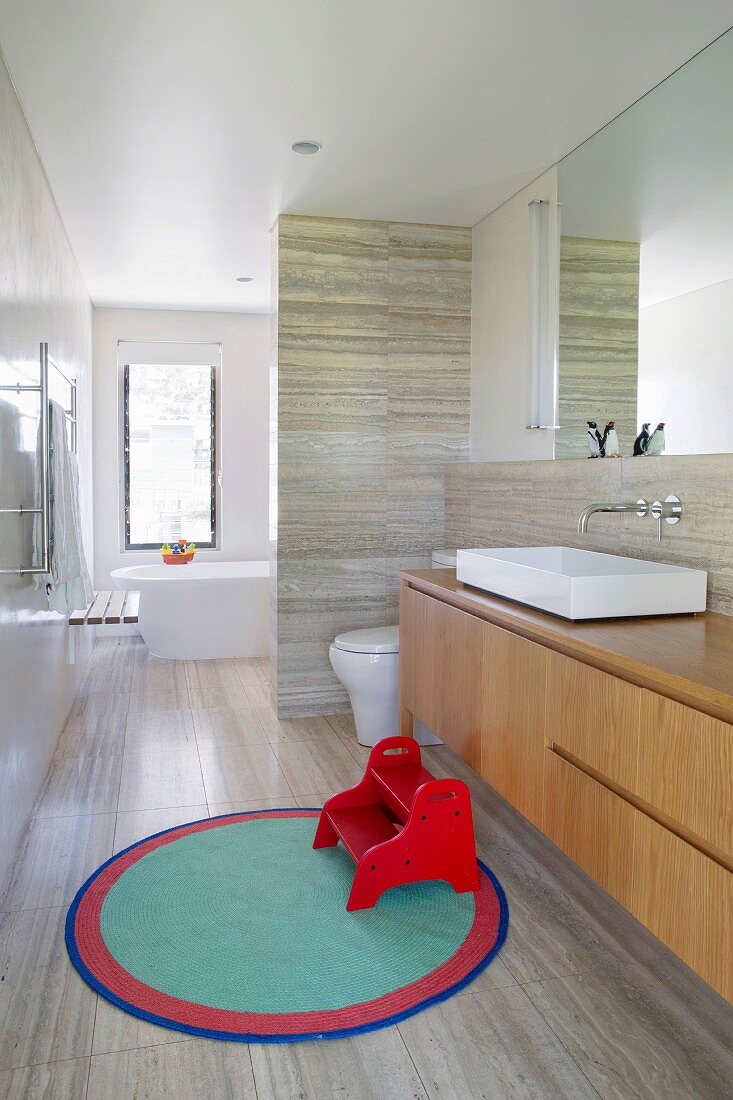 Elegant designer bathroom with natural stone cladding and elegant washbasin base
