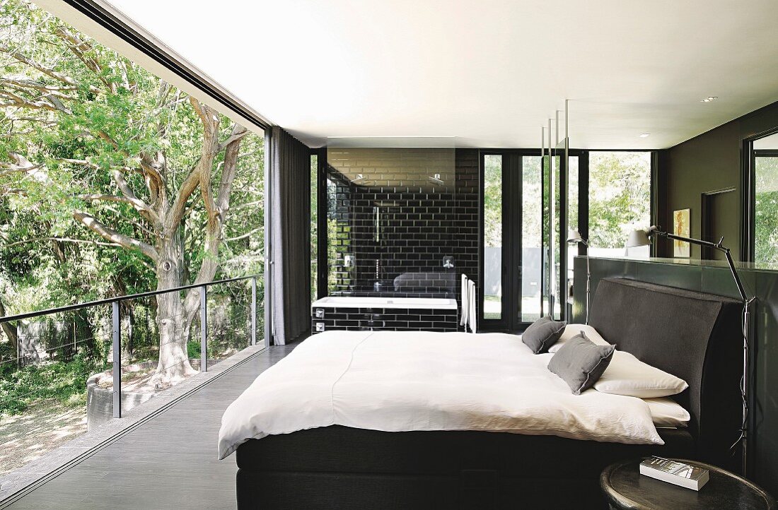 Bedroom with ensuite bathroom and sliding glass wall with view of garden