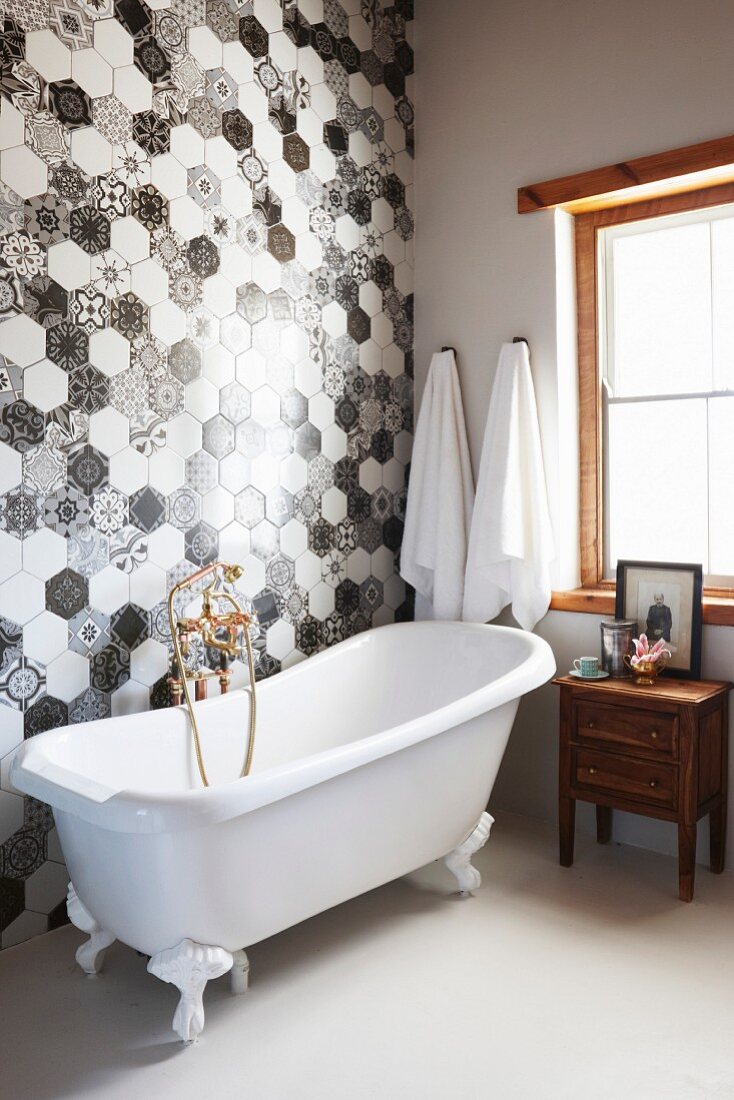 Vintage-style bathtub against black and white hexagonal wall tiles